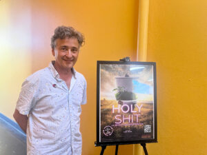 Rubén Abruña al lado del afiche del documental "Holy Shit: La revolución regenerativa"
