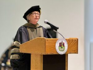 Wanda T. Maldonado Dávila, Catedrática y Decana de la Escuela de Farmacia de la Universidad de Puerto Rico, detrás de un podio.