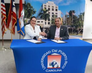 Dr. José Ignacio Meza Pereira, rector del recinto carolinense, y la señora Lourdes M. Aponte Rodríguez, actual presidenta del Centro Unido de Detallistas, dándose la mano después de haber firmado el acuerdo colaborativo.