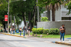 foto estudiantes caminando por la acera frente a un edificio en el Recinto de Río Piedras