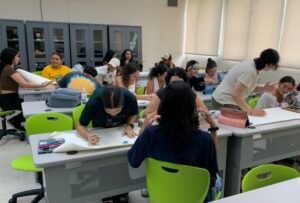 Estudiantes de UPR Cayey y Florida Atlantic University haciendo sentados en varias mesas haciendo investigación en un salón.