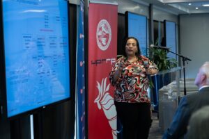 Dra. Theany Calderón, profesora de la Facultad de Administración de Empresas de la UPR recinto de Río Piedras en tarima dando una presentación.