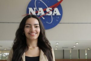 Estudiante del RUM Frente al logo de la NASA