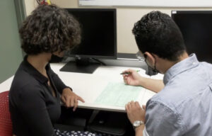 Estudiante siendo atendido.  Le están ayudando a llenar la planilla federal.