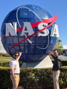 Dr. David Suleiman Rosado, director y catedrático del Departamento de Ingeniería Química (INQU) del RUM y el candidato doctoral, Juan Camilo Rivera Díaz frente a logo esférico de la NASA